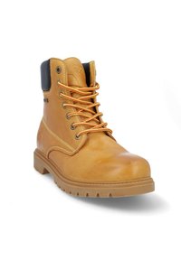 Bota de trabajo de cuero marrón con cordones naranjas, cuello acolchado y suela de goma con un patrón de banda de rodadura robusto. Detalles de costura en los laterales.