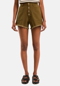 Aukšto juosmens alyvuogių spalvos šortai su penkiomis sagomis, dviem priekinėmis kišenėmis ir aptrintais kraštais. Derinami su juodais sandalais, puoštais auksiniais akcentais.