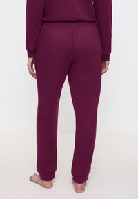 Burgundy loungebyxor med elastisk midja, med en mjuk textur och rak bendesign, synliga sömmar och inga bakfickor.
