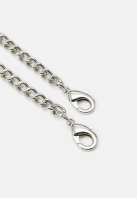 Srebrny łańcuch z owalnymi ogniwami i dwoma zapięciami typu lobster na każdym końcu. Gładkie wykończenie metalowe o błyszczącym wyglądzie.