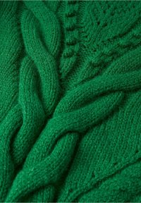 Smaragdgroene gebreide trui met ingewikkelde kabelpatronen, textuursteken en kleine verhoogde accenten door de stof.