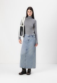 Gray long-sleeve turtleneck, light blue denim maxi skirt, black ankle boots with metal accents, and a textured white and black shoulder bag.