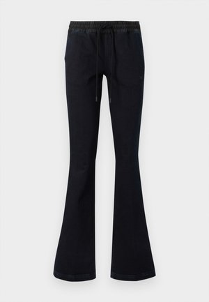 Σκούρα μπλε τζιν με φαρδιά καμπάνα, ελαστική μέση και μαύρο κορδόνι, παρουσιάζονται πάνω σε λευκό απλό φόντο.