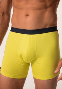 Bóxer de mezcla de algodón amarillo con una cinturilla elástica negra, con una textura suave y un silueta ajustada.