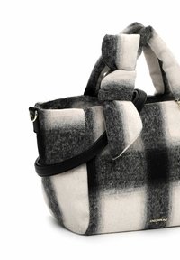 Schwarz-weiß karierte Handtasche aus weichem Stoff mit geknoteten Griffen und verstellbarem schwarzen Schultergurt, kleines goldenes Logo unten rechts.