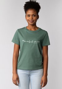 Groene katoenen T-shirt met korte mouwen en ronde halslijn. Voorzien van witte tekst "so einfach ist das" die op de voorkant is gedrukt.