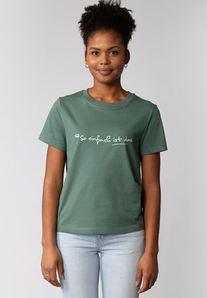 T-shirt en coton vert à manches courtes et col rond. Présente un texte blanc, "si simple est cela," imprimé sur le devant.