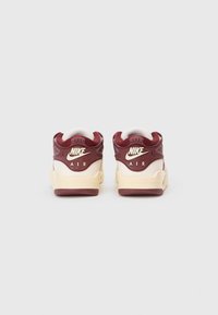 Par u duboko crvenih i krem bijelih Nike Air tenisica prikazanih s leđa na običnoj bijeloj pozadini.