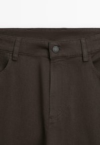 Pantaloni in cotone marrone con taglio dritto, chiusura con bottone e tasche anteriori con finitura testurizzata.