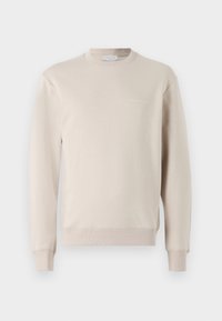 Beżowa bluza wykonana z miękkiej bawełny, z okrągłym dekoltem, długimi rękawami oraz subtelnym logo na piersi. Gładka faktura.