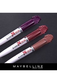 Tre Maybelline Super Stay 24 Color läppprodukter i nyanser av mörk lila, djup ros och nude, uppvisade med swatches på en mörk bakgrund.