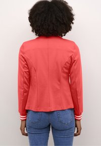 Czerwona kurtka o dopasowanym kroju, z długimi rękawami i mankietami w paski. Gładki materiał i wyraźne szwy nadają jej fasonowany wygląd.