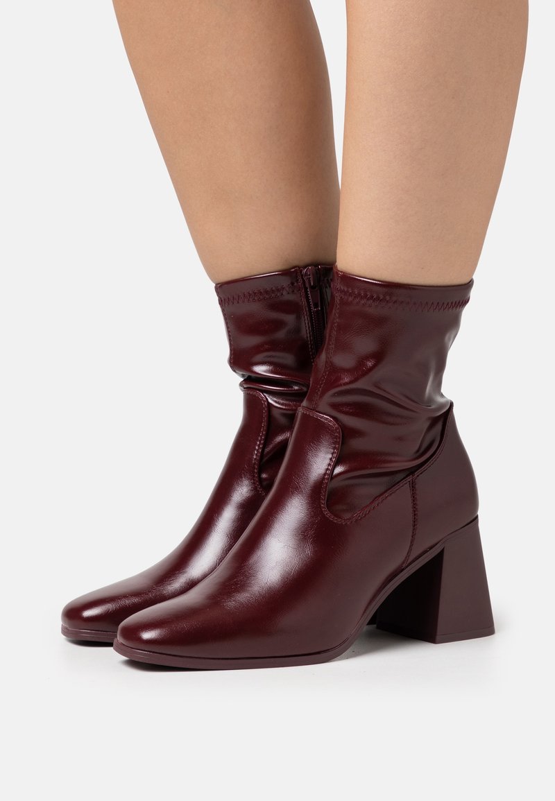 Bottines en fausse cuir bordeaux avec un bout carré et un talon bloc moyen, dotées d'une fermeture éclair et d'un design supérieur froncé pour la texture.