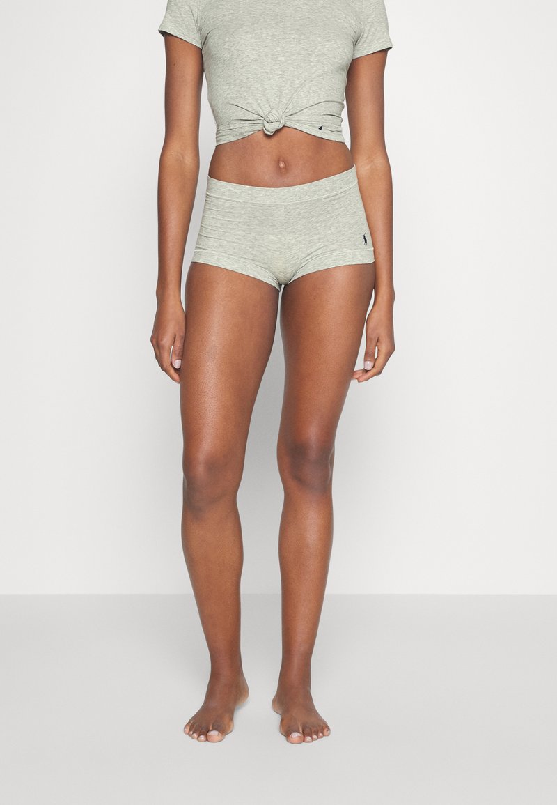 Sivý krátky bavlnený top s krátkym rukávom zviazaný v páse, skombinovaný s vyhovujúcimi šortkami s vysokým pásom. Mäkká textúra, minimálne detaily a priliehavý strih.