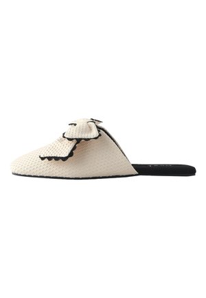 Beige tekstureret flad mule sko med sort kant og stor sløjfedetalje på toppen samt sort sål og inderside.