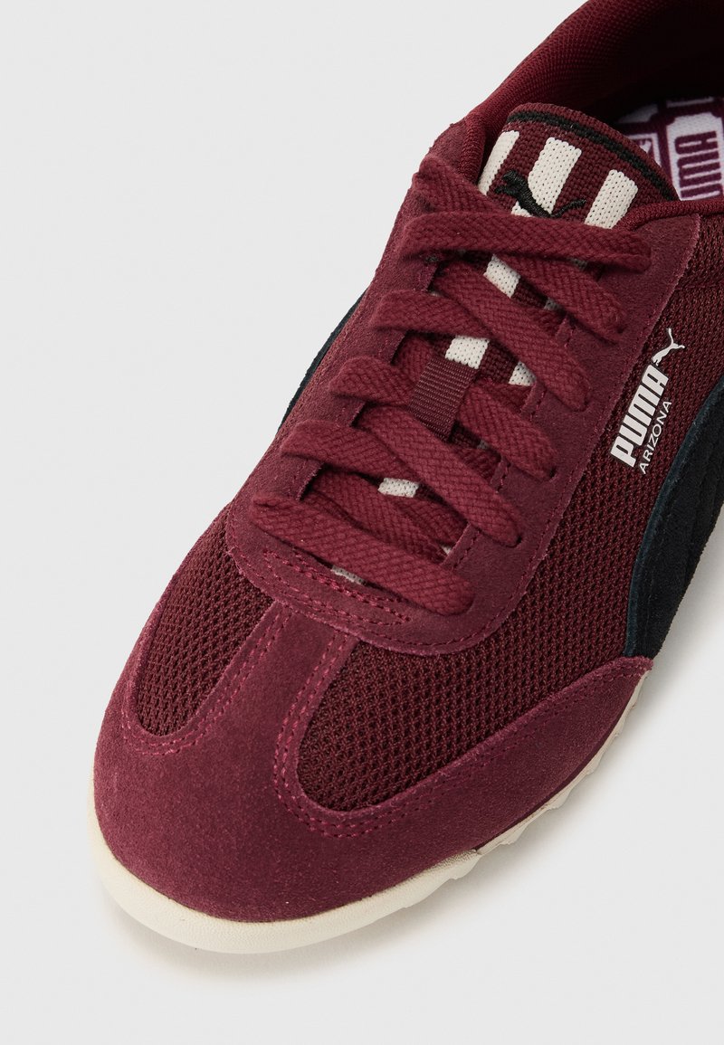 Bordeaux sneaker van mesh en suède materialen, met zwarte accenten, vetersluiting en een getextureerde witte zool. PUMA-logo zichtbaar.