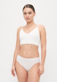 White sports bra with adjustable straps and a v-neck design, paired with matching briefs. Soft, stretchable fabric ensures comfort.