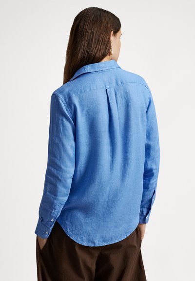 Svetlomodrá košeľa s dlhým rukávom z textúrovaného materiálu, s zaobleným lemom, zadným záhybom a manžetami na gombíky.
