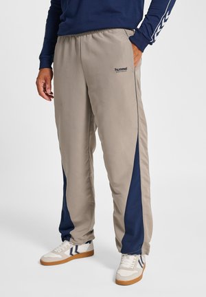 Beige trainingsbroek met marineblauwe zijpanelen, elastische tailleband en een "hummel"-logo. Gemaakt van gladde stof, met een ontspannen pasvorm.