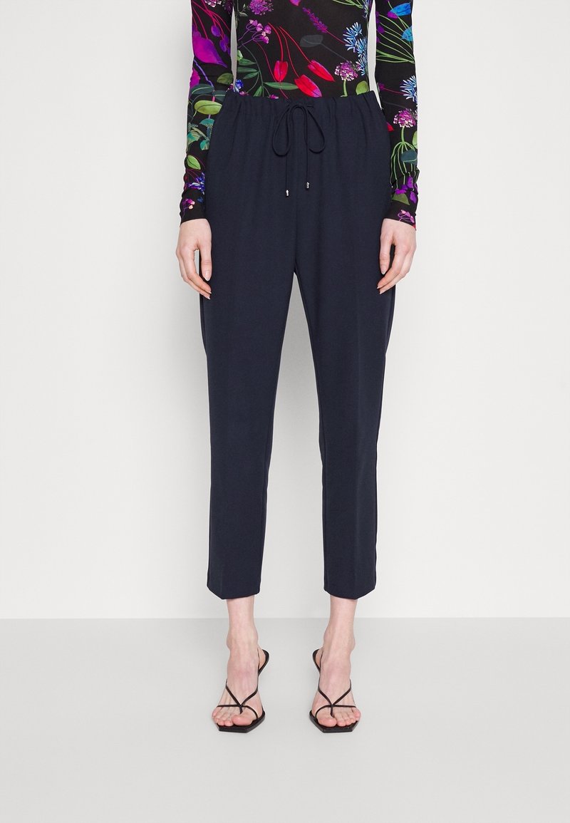 Pantalon léger bleu marine avec une ceinture élastique et un cordon de serrage ajustable. Comprend des poches latérales et des jambes fuselées avec une longueur raccourcie.