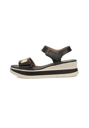Sandalias de cuña de cuero negro con un acabado texturizado, acento triangular y suela acolchada. Cuenta con correas ajustables para mayor soporte.