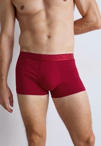 Boxeri scurți din bumbac roșu, cu o textură netedă, design ajustat și o talie cu un model subtil. Concepuți pentru confort și suport.