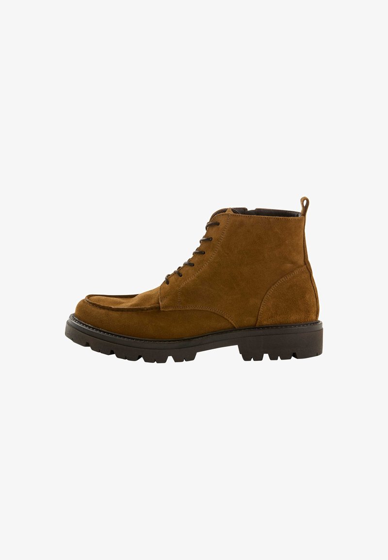 Stivale alla caviglia in suede marrone con lacci, dotato di suola in gomma nera spessa e linguetta sul retro, mostrato di lato su sfondo bianco.