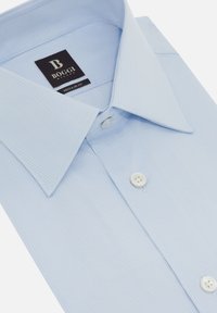 Camicia a righe blu chiaro in cotone. Vestibilità regolare, con colletto aperto e bottoni bianchi sulla patta. Etichetta visibile.