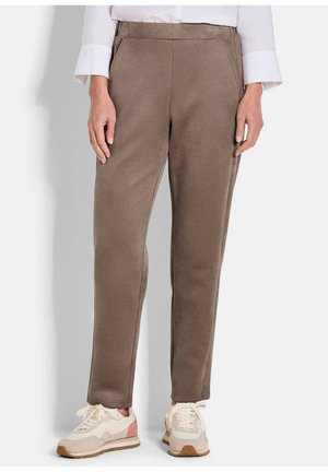 Braune, schmal geschnittene Hose aus weichem Stoff mit glatter Textur. Verfügt über Seitentaschen und einen Bund. Kombiniert mit weißen und rosa Sneakers.