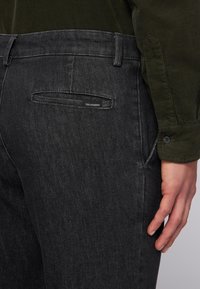 Czarne dżinsy o slim fit, z tylną kieszenią z małym logo marki. Tkanina ma subtelną teksturę i jest średniej grubości.