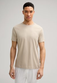 Beige t-shirt met korte mouwen van zachte stof met een ronde halslijn en een klein logo op de linkerborst. Draag het met witte broeken.