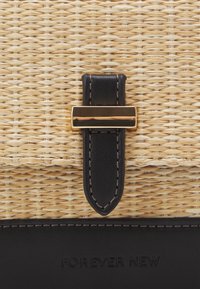 Borsa a tracolla in paglia intrecciata con dettagli in pelle nera e chiusura in tono oro. Presenta texture a contrasto e un marchio in rilievo ben visibile.