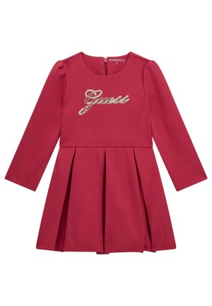 Robe en coton rouge à manches longues avec une jupe plissée, présentant un logo "Guess" pailleté sur la poitrine et une fermeture éclair dans le dos.