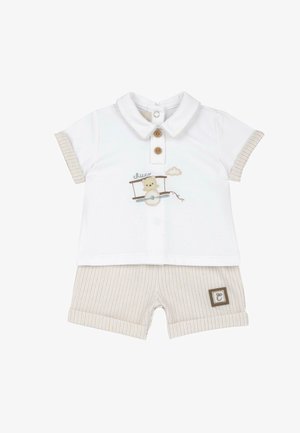 Ensemble bébé blanc avec col et boutons, un ours pilotant un avion brodé sur la chemise, associé à un short beige rayé avec détail de revers.