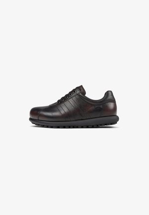 Black leather sneaker with textured sides, six eyelets, rounded toe, and a rubber sole featuring small circular grips.