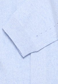 Pull bleu clair avec une texture douce en maille. Présente des poignets et des coutures côtelés, mettant en valeur un design épuré et simple.