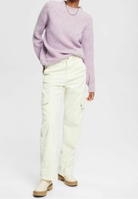 Pull tricoté violet clair avec motif texturé, porté avec un pantalon cargo en velours côtelé blanc cassé et des chaussures beige à enfiler.