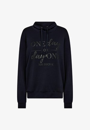 Tengerészkék pulóver magas nyakkal, húzókkal és fémes betűzéssel, amely azt mondja: "Egyik nap vagy az első nap, te döntesz." Puha anyag, laza szabás.