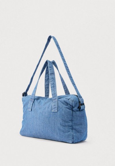 Modra oblazinjena pravokotna ramenska torbica z dvema ročajema za roke in nastavljivim dolgim trakom, prikazana na enostavni svetli podlagi.