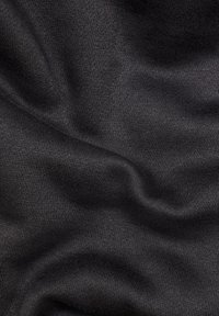 Texturerad mörkgråt tyg med ett slätt stickat mönster och subtila nyansvariationer, som visar mjuka veck och draperingar.