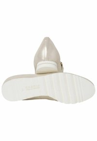 Beige højhælede sko med en glat, shiny overflade. Hvid tekstureret gummisål med riller og et subtilt logo. Skrå hæl for stabilitet.