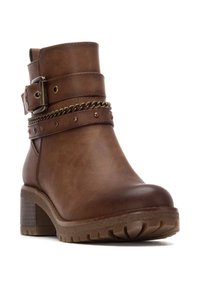 Botín de cuero marrón con tacón grueso, hebilla decorativa, detalle de cadena y remaches. Lateral texturizado y suela con perfil para mayor agarre.