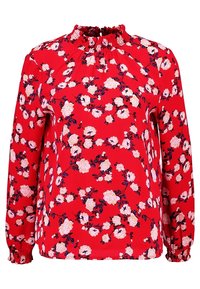 Blouse florale rouge à manches longues, avec un col smocké, ornée de roses blanches et roses accompagnées de feuilles vertes sur un fond rouge vif.