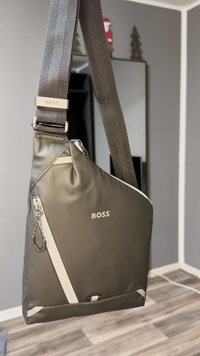 Sling bag made of gray nylon, featuring a triangular design, white accents, a silver zipper, and an adjustable strap with the "BOSS" logo.