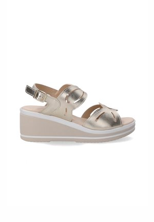 Sandales compensées avec un dessus en cuir doré métallisé, design découpé, sangle de cheville réglable et une semelle compensée beige avec des accents blancs.