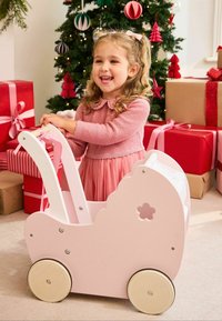 Puidust nukuvanker pehme roosa tooniga, ümmarguste servade ja lillelõikega. Varustatud puidust rataste ja valge kangasealdisega.