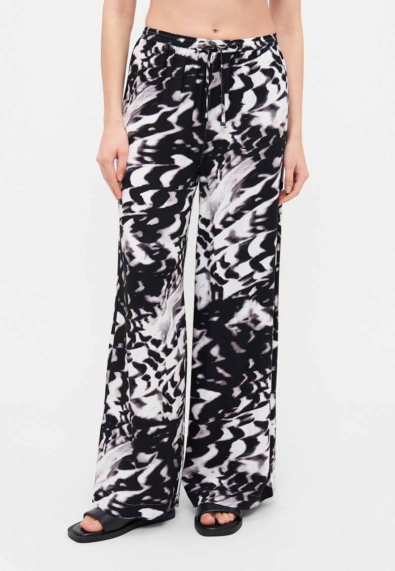 Pantalones anchos de patrón en blanco y negro con cinturilla elástica y detalle de cordón, hechos de una tela suave y ligera.