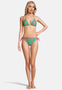 Ensemble de bikini avec une base verte et de bold motifs géométriques roses. Haut en triangle avec des liens et bas avec des liens sur les côtés pour un ajustement réglable.