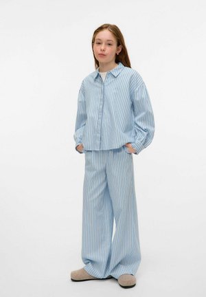 Lyseblå stribet skjorte og brede bukser lavet af blødt stof, med en afslappet pasform og manchetter. Matchet med lyse slippers.