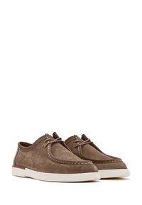 Scarpe in suede marrone con forma arrotondata, suola in gomma bianca e cuciture a contrasto. Presentano lacci e un leggero tacco.